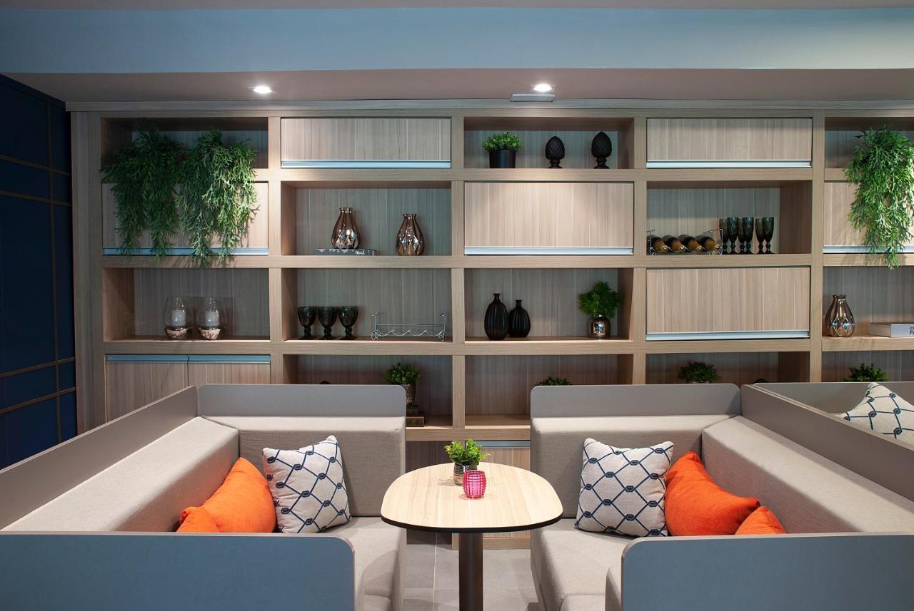 Wyndham Gramado Termas Resort & Spa Ngoại thất bức ảnh The photo shows a modern seating area featuring two low, comfortable sofas arranged in an L-shape. The sofas are upholstered in a light grey fabric with decorative cushions in orange and a patterned design. In the center, there's a small round table 