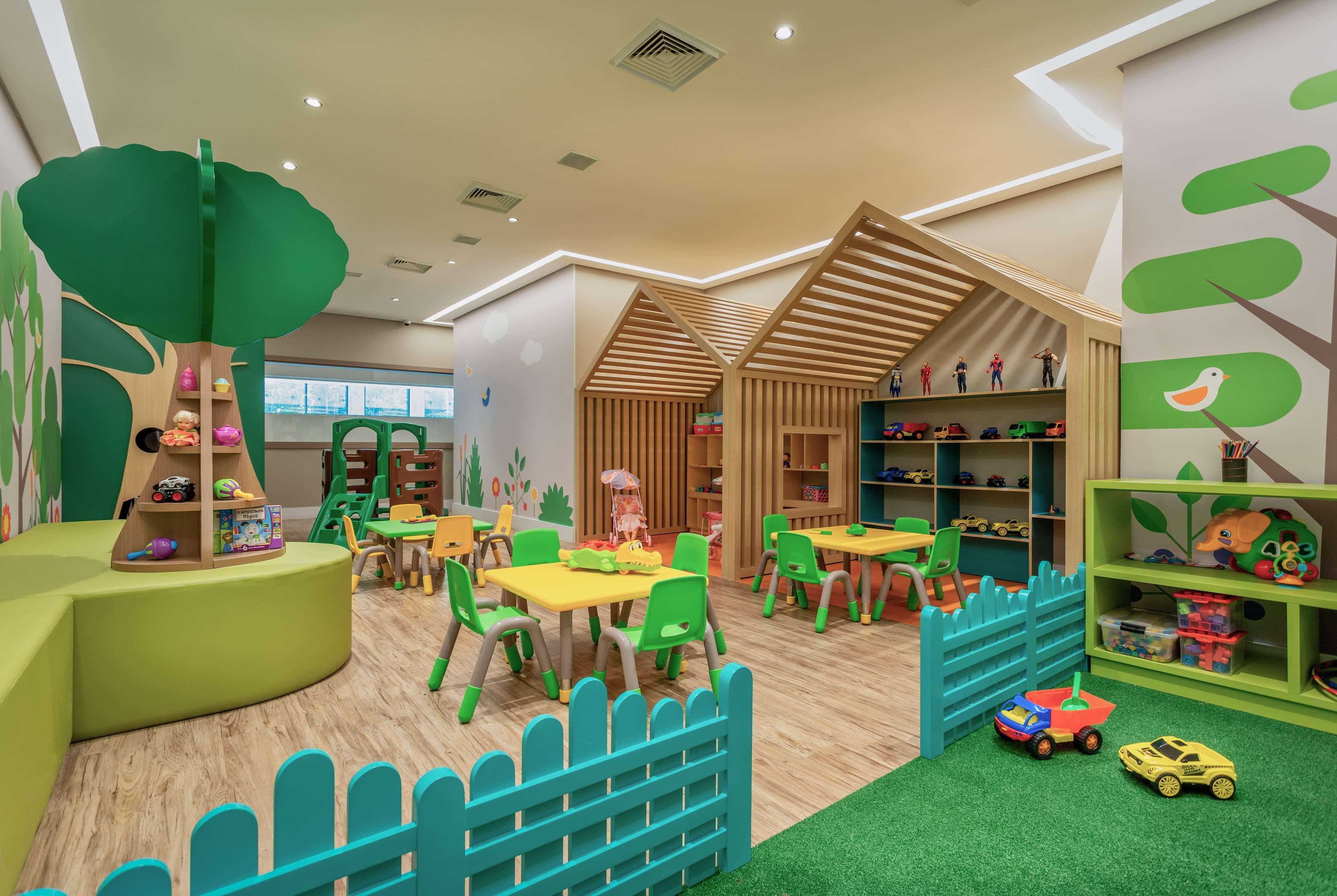 Wyndham Gramado Termas Resort & Spa Ngoại thất bức ảnh The photo shows a vibrant and playful children's playroom. There are colorful furniture pieces, including green chairs and yellow tables arranged for activities. On one side, there are wooden structures resembling small houses, and shelves are filled
