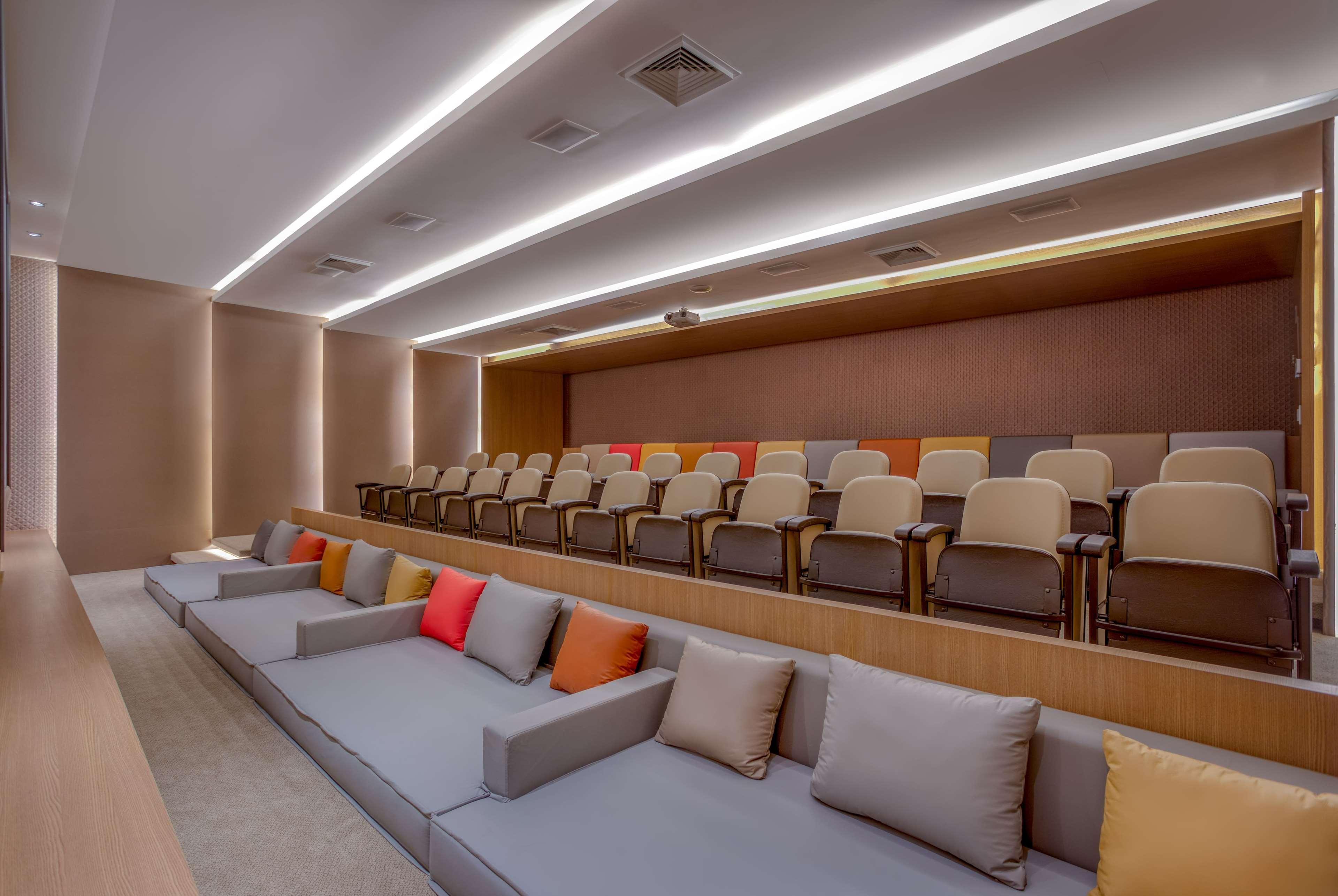 Wyndham Gramado Termas Resort & Spa Ngoại thất bức ảnh The photo depicts a modern auditorium or presentation room. It features tiered seating with rows of comfortable chairs and a seating area at the front that has a long sofa with several colorful pillows. The lighting is sleek and ambient, with recesse