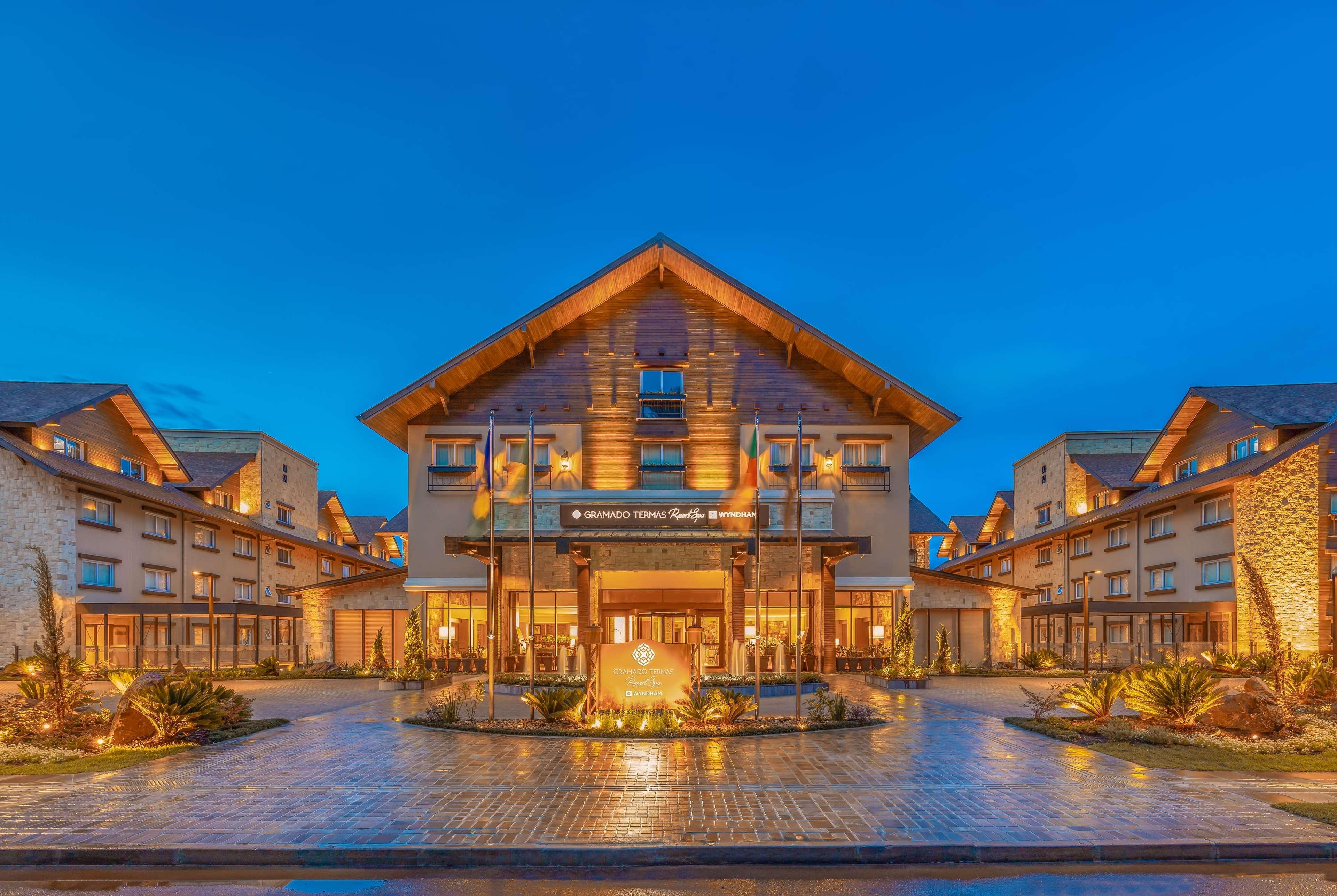 Wyndham Gramado Termas Resort & Spa Ngoại thất bức ảnh The photo shows the exterior of a lodge or hotel. The building features a modern yet rustic design, characterized by wooden elements and a peaked roof. It is illuminated with warm lighting, creating an inviting atmosphere. The entrance is accentuated