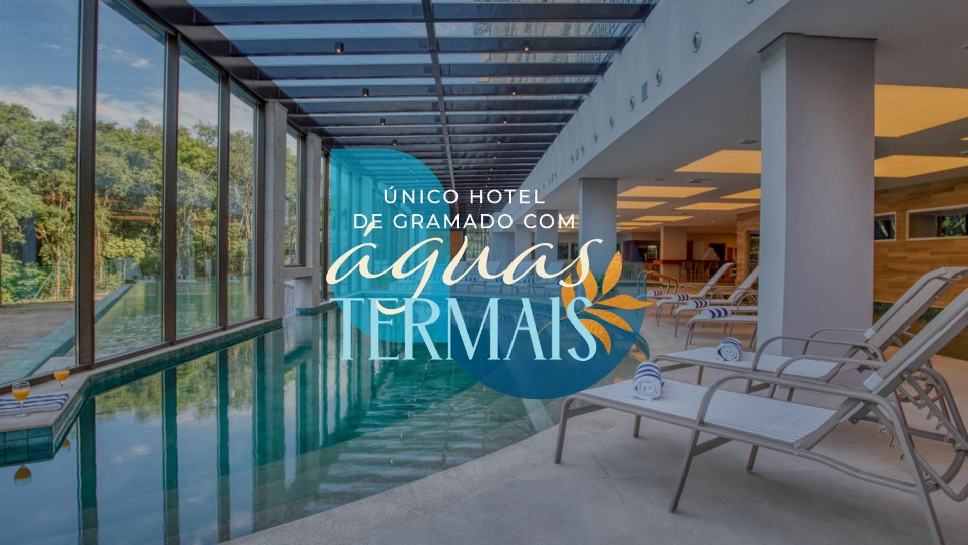 Wyndham Gramado Termas Resort & Spa Ngoại thất bức ảnh The photo shows the interior of a hotel featuring a swimming pool, complemented by large glass windows that allow natural light to enter. The setting appears serene and modern, with lounge chairs arranged around the pool area. Text overlay on the ima