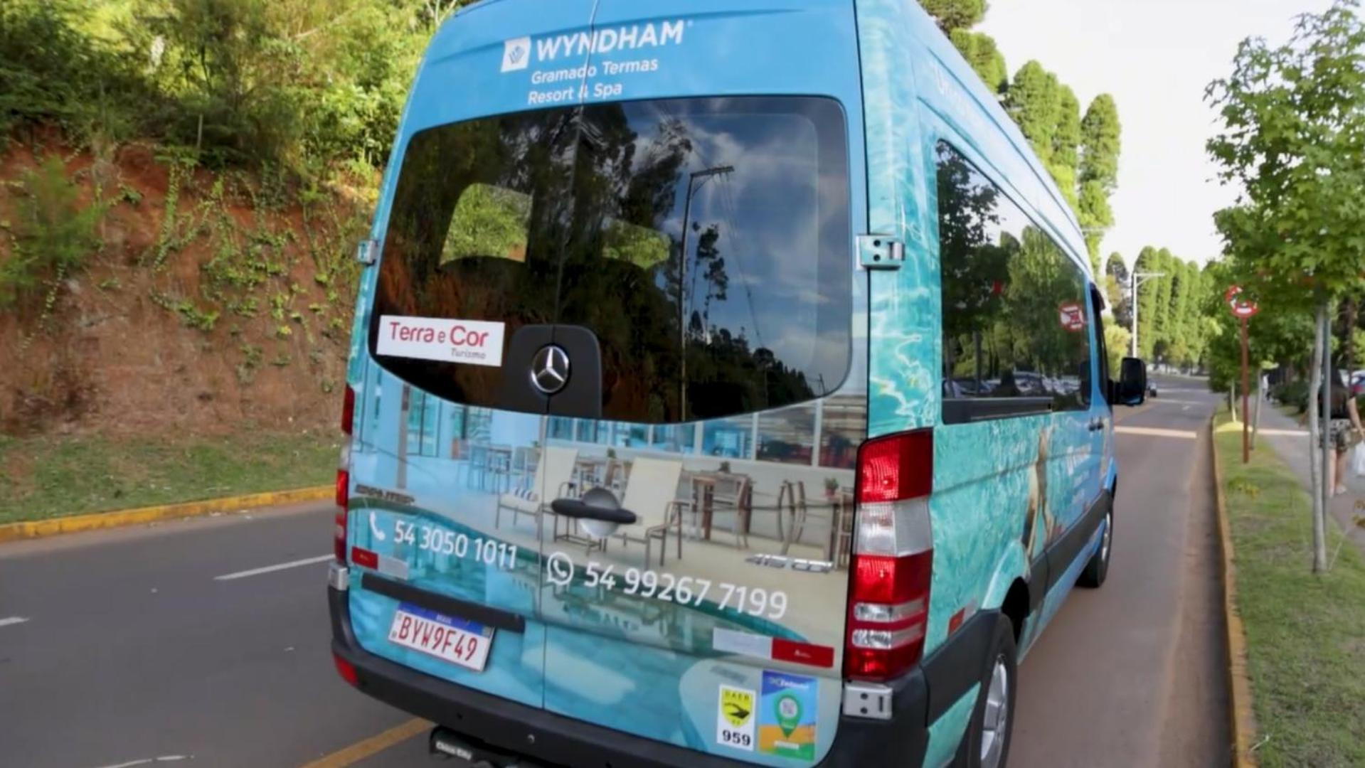 Wyndham Gramado Termas Resort & Spa Ngoại thất bức ảnh The image shows the rear side of a van or shuttle bus. The van is wrapped in a promotional design featuring the Wyndham hotel brand, with an advertising message for "Terra & Cor." The vehicle includes contact numbers and a logo. It appears to be on a