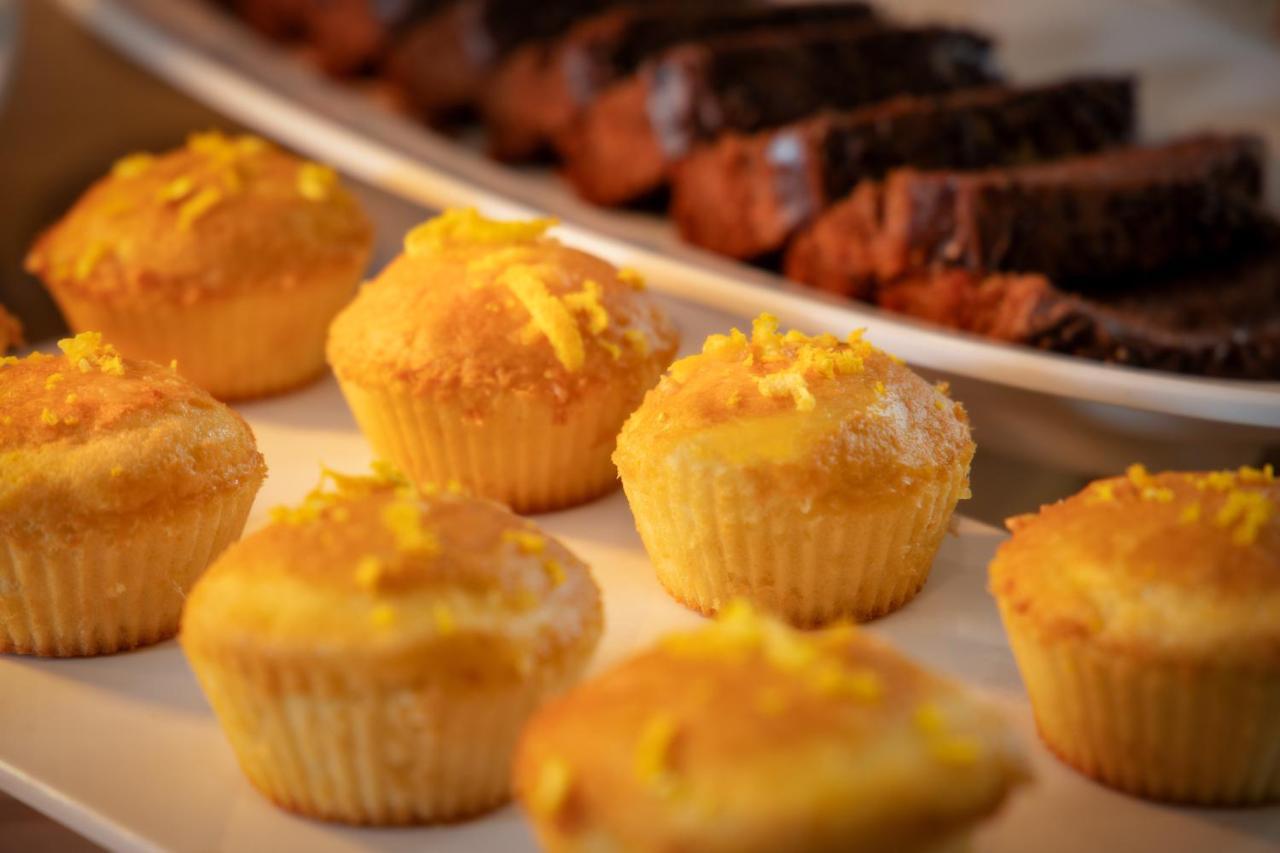 Wyndham Gramado Termas Resort & Spa Ngoại thất bức ảnh The image features a platter of baked goods, prominently displaying a row of light yellow cupcakes decorated with what appears to be a sprinkle of yellow zest on top. In the background, there are slices of darker baked goods, likely chocolate bread o