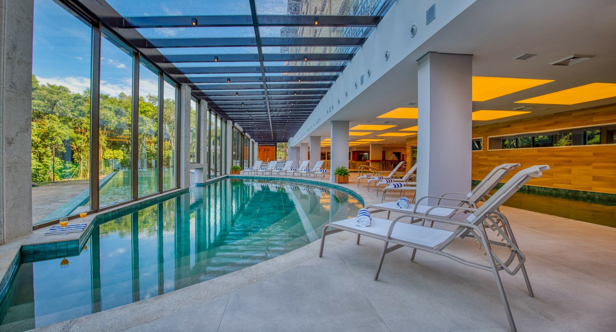 Wyndham Gramado Termas Resort & Spa Ngoại thất bức ảnh The photo shows an indoor swimming pool area featuring a modern and elegant design. The pool has clear water and is surrounded by large glass windows that allow natural light to flood in, providing a scenic view of the outdoors. There are several lou